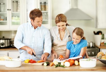 Young girl helping her parents make a salad